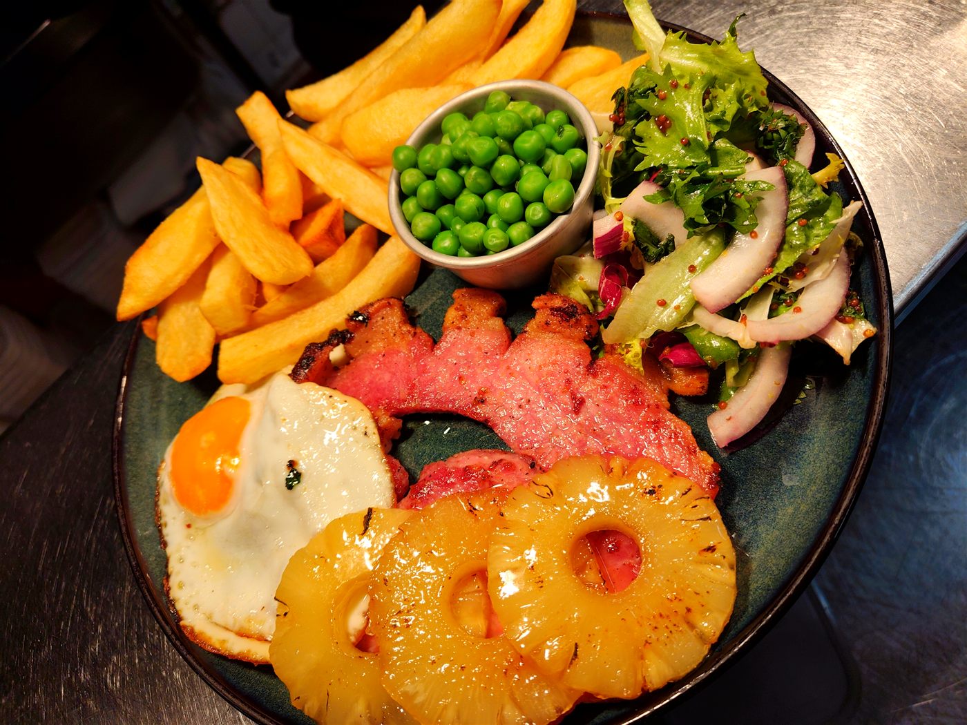 Gammon steak with fried egg, grilled pineapple, chips, peas and salad