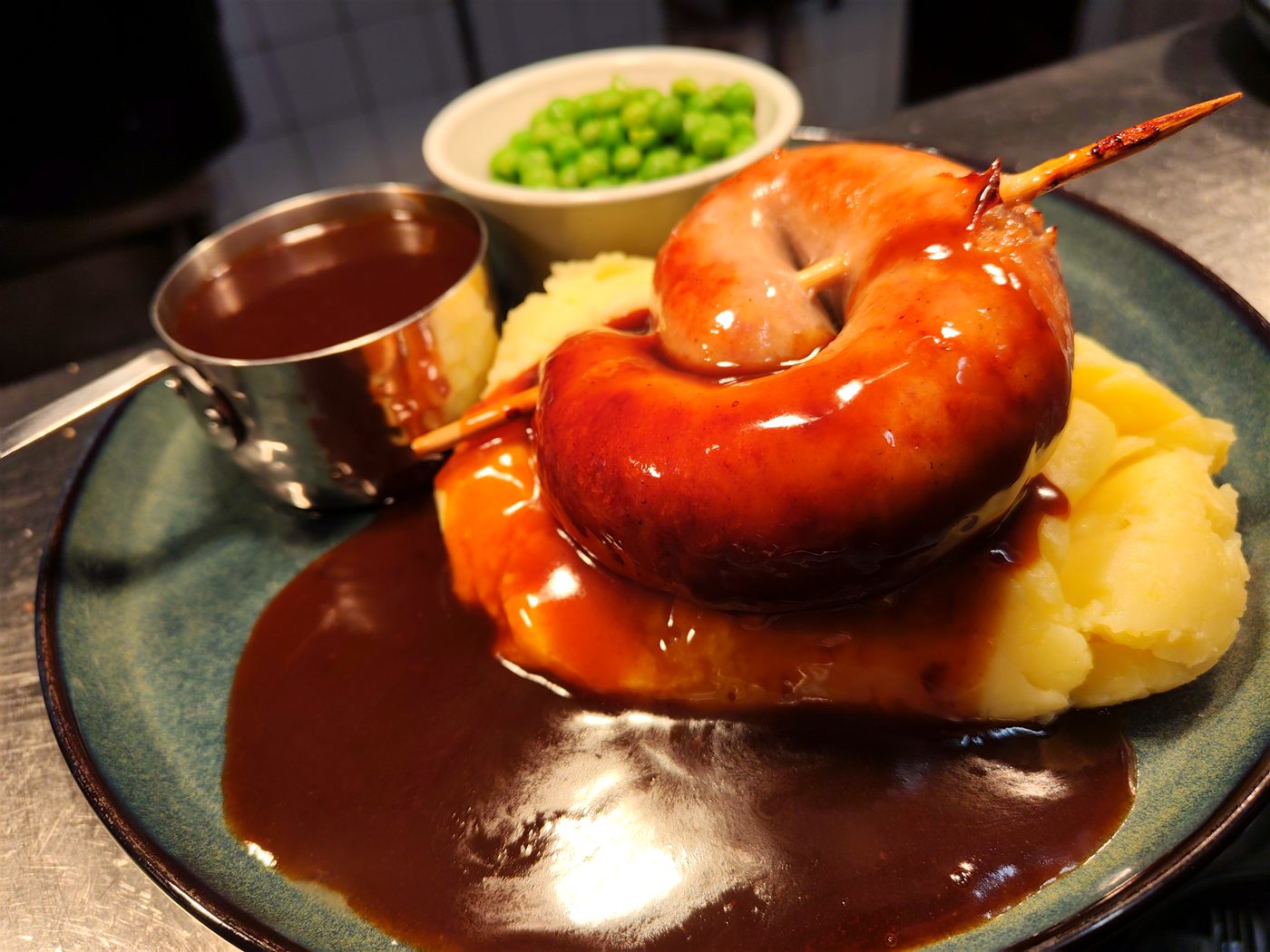 Cumberland sausage ring with creamy mash, gravy and garden peas