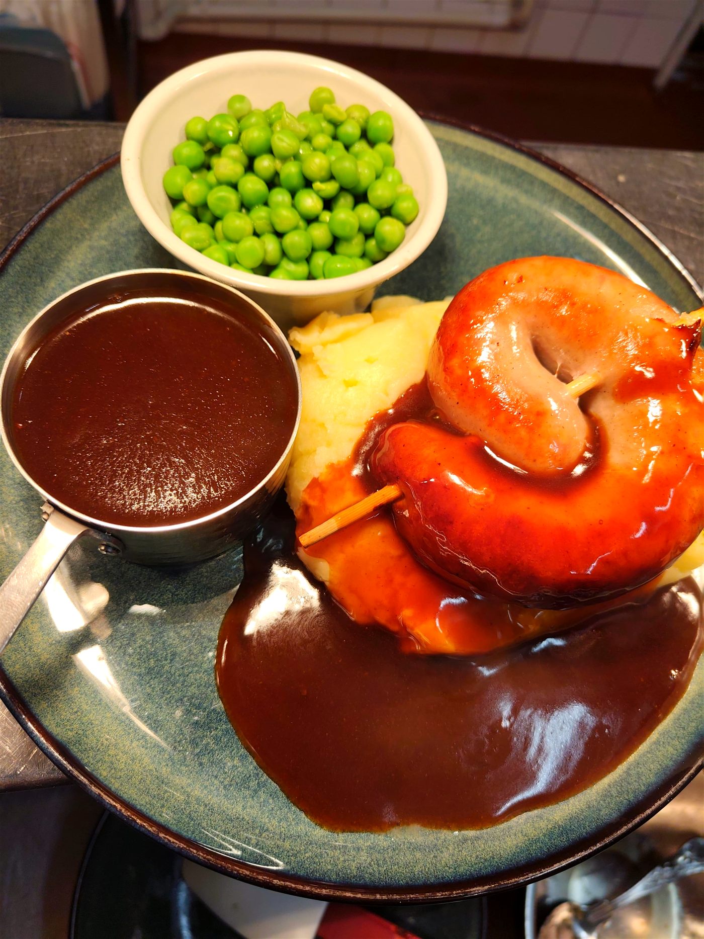 Cumberland sausage ring on creamy mash with rich gravy and peas
